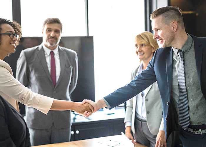 business people shaking hands translators next to them